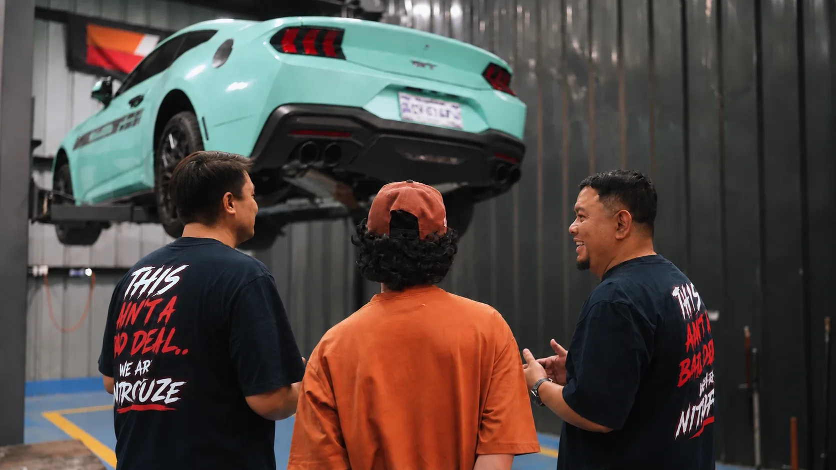 Ronald and Wallen walking a customer through his finished Mustang build on the lift