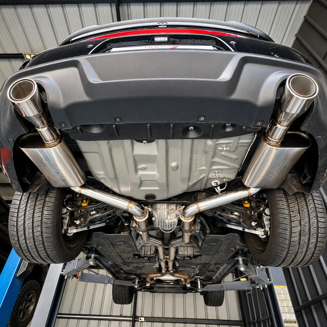 Underside of a Dodge Charger on the lift showing the stainless dual catback, Borla ATAK mufflers and dual Borla tips