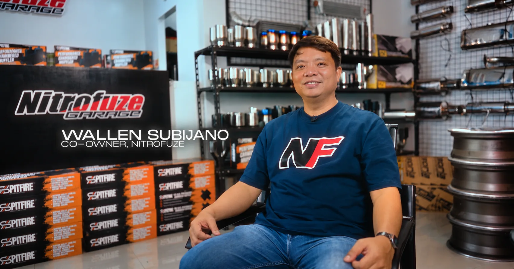 Wallen Subijano seated in the Nitrofuze showroom in front of Spitfire muffler boxes