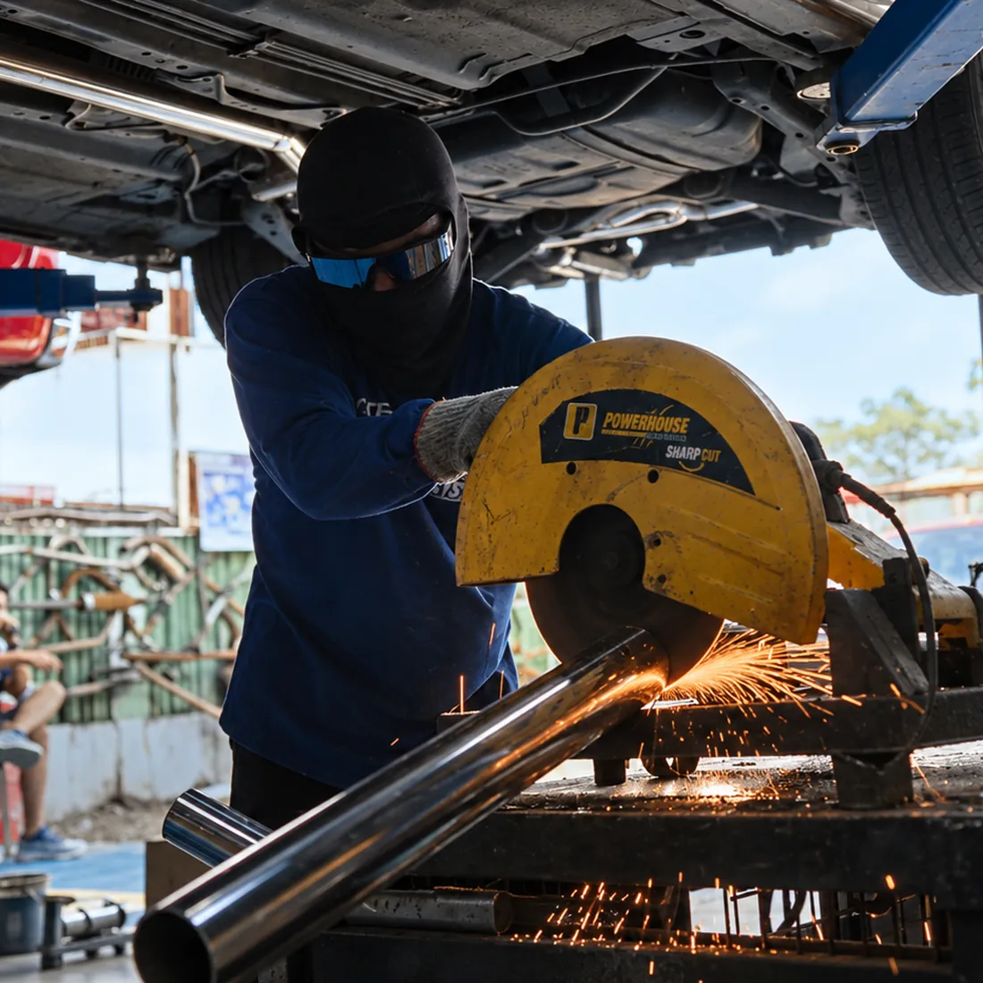 A Nitrofuze fabricator cutting stainless exhaust pipe with sparks flying